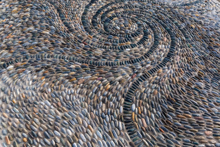 Part of footpath paved with multicolored pebbles and small cobblestones, view in sunny morningの写真素材