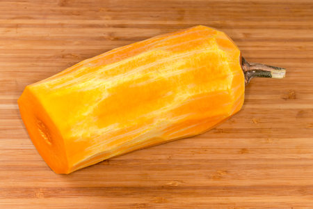 Half of the butternut squash from the stem side cut across, peeled from skin on the wooden surfaceの写真素材