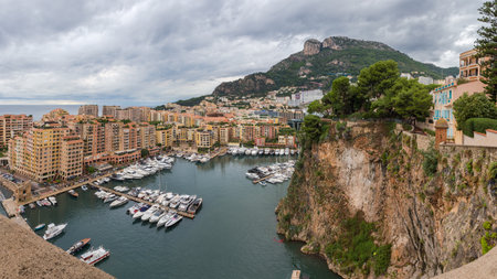 Harbor Fontvieille and clinging urban district in the western part of the Monaco against the mountains and cloudy sky, general panoramic view from the Rock of Monaco at autumn rainy dayの写真素材