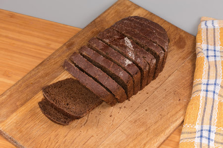 Sliced rectangular oblong loaf of the brown bread made from rye and wheat flour on the wooden...
