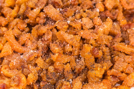 Heap of cracklings obtained by long melting from duck fat and skin slices, seasoned with salt and ground pepper, view close-up in selective focusの写真素材