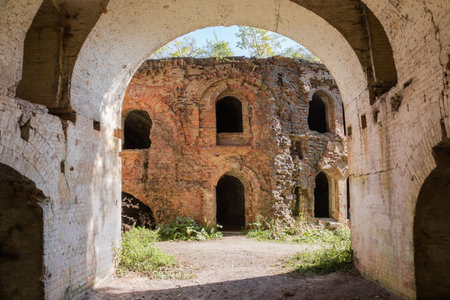 Partly ruined defensive buildings made with red brick with arched window and door openings in old fortress, view in autumn sunny dayの写真素材