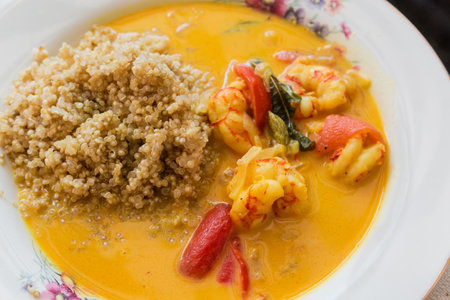 Porridge of white quinoa with shrimps and tomatoes on the dish, fragment close-upの写真素材