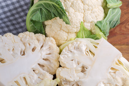 Two halves and one whole head of the fresh raw cauliflower with some leaves, top view of fragment close-upの写真素材
