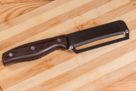 Kitchen knife with plastic handle, stainless steel blade and guide bar for accurate even slicing into identical pieces lies on a wooden bamboo cutting boardの写真素材