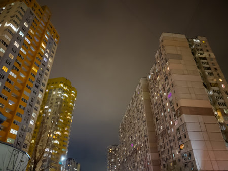 Multi story apartment buildings in modern housing estate, bottom view against the cloudy sky at nightの写真素材