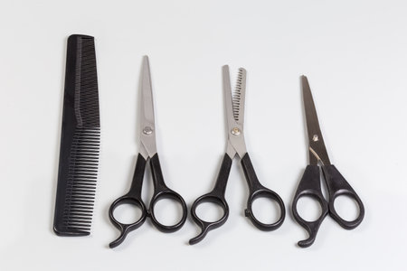 Several pairs of the professional stainless steel normal scissors and hair thinning scissor, one plastic comb on a gray backgroundの写真素材