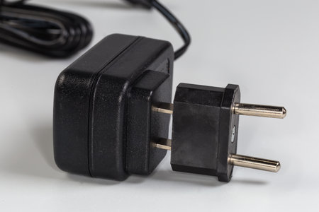 Power unit for various gadgets with American AC two-pronged plug with partially connected adapter to...