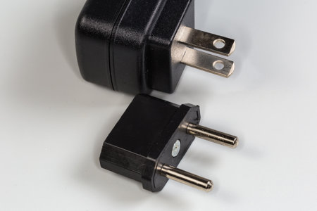 AC adapter from the American two-pronged plug to the Euro plug against the power unit on a gray...