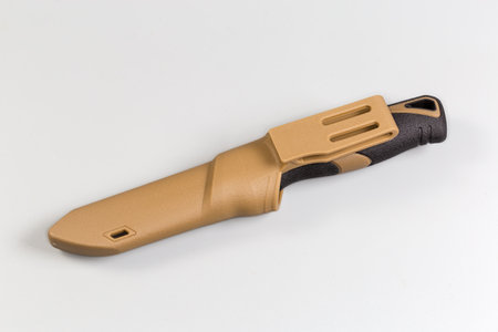Tourist knife with fixed blade and ergonomic plastic handle in the plastic sheath with fastening for attaching to a trouser belt on a gray backgroundの写真素材