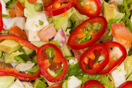 Salad with soft cheese, avocado, various lettuce, sliced sweet pepper Kapia and other different fresh vegetables in kitchen stainless steel bowl, top view close-upの写真素材