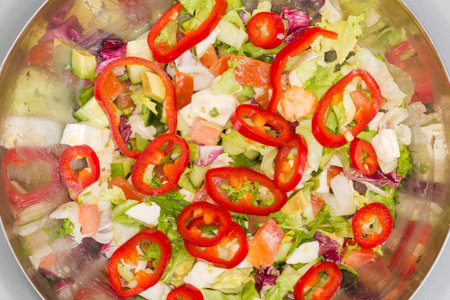 Salad with soft cheese, avocado, various lettuce, sliced sweet pepper Kapia and other different fresh vegetables in kitchen stainless steel bowl, top viewの写真素材