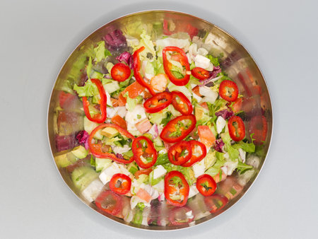 Salad with soft cheese, avocado, various lettuce, sweet pepper Kapia and other fresh vegetables in kitchen stainless steel bowl, top view on a gray backgroundの写真素材