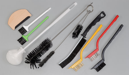 Manual brushes of different designs for various purposes with bristles different hardness made with plastic and metal materials on a gray surface, top viewの写真素材