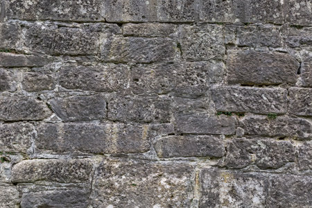 Wall of bastion of an ancient castle clad with rough rectangular stone blocks hewn of sandstone in shade, fragment close-upの写真素材