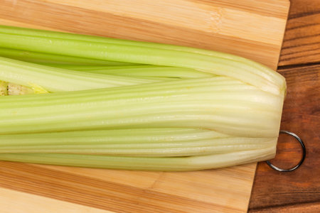 Fresh stems of celery on a wooden cutting board, top view of fragment close-upの写真素材