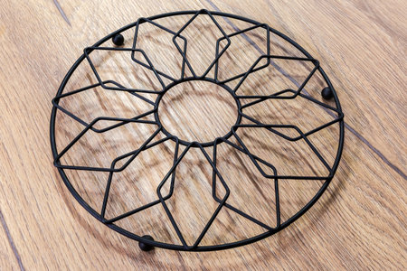 Kitchen stand under the hot made with black iron wire of different thicknesses on a wooden tableの写真素材