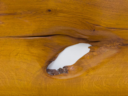 Texture of the varnished wooden plank made of cracked oak wood with hole in place of a fallen knotの写真素材