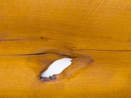 Texture of the varnished wooden plank made of cracked oak wood with hole in place of a fallen knotの写真素材
