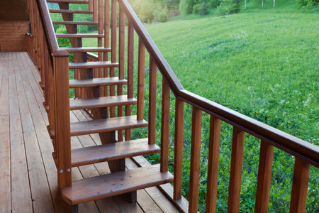 External straight wooden stairs of the building with handrail against the lawn at sunset backlitの写真素材