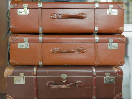 Stack of the closed old big rectangular-shaped old-fashioned shabby hardshell suitcases, made with leatherette of different colorの写真素材