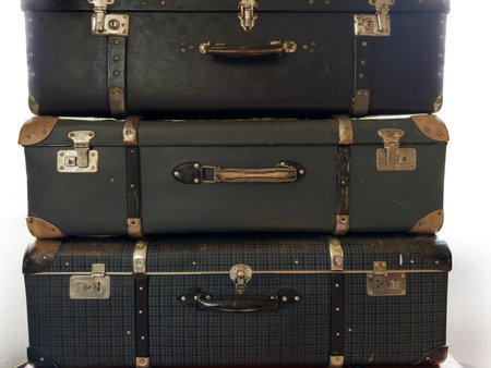 Stack of the closed old big rectangular-shaped old-fashioned shabby hardshell suitcases, made with leatherette on a white backgroundの写真素材