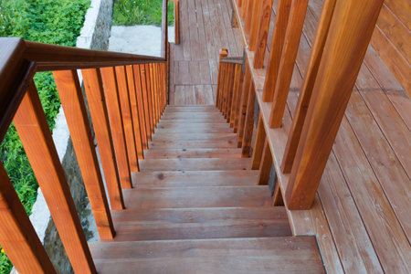 External straight wooden stairs of the building with handrail in sunny evening, top down viewの写真素材