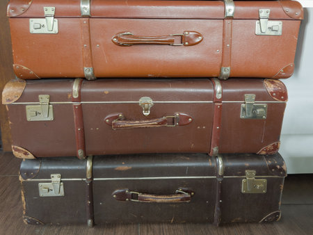 Stack of the closed old rectangular-shaped old-fashioned shabby hardshell suitcases made with leatherette of different colorの写真素材