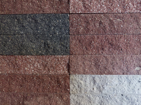 Part of the building wall faced with rectangular stone tiles different color with rough front surfaceの写真素材