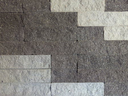 Part of the building wall faced with rectangular gray stone tiles different shades with rough front surfaceの写真素材