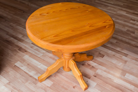 Wooden table on one leg with round table top stand in room with wooden flooring, close-up in selective focusの写真素材