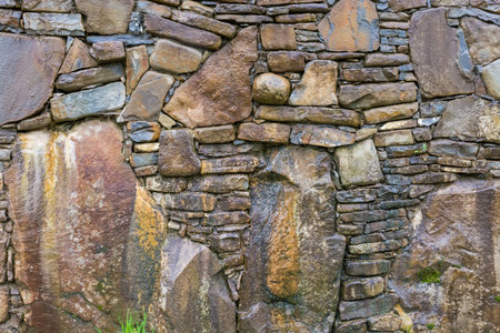 Surface of the wet rough retaining wall built with natural stones different forms, colors and sizes, including large boulders in rainy overcast dayの写真素材