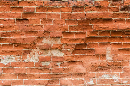 Fragment of the ancient rough red brick wall with partially crumbled old bricks close-upの写真素材