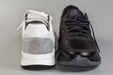 Toecap of black and back of white-gray leather sneaker of classic style with lacing on a gray background, view in selective focusの写真素材