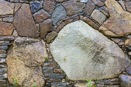 Surface of the wet rough retaining wall built with natural stones different forms, colors and sizes, including large boulders in rainy overcast dayの写真素材