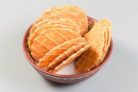Sweet round thin flat crisp wafers in the small clay bowl on a gray backgroundの写真素材