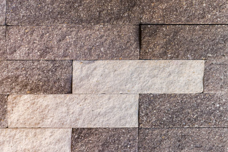 Part of the building wall faced with rectangular gray stone tiles different shades with rough front surface in a decorative pattern, texture, background,の写真素材