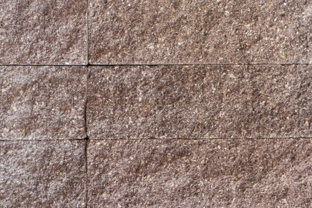 Part of the building wall faced with decorative rectangular gray stone tiles with rough front surface, texture, background,の写真素材