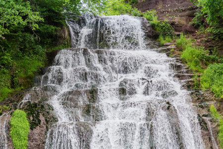 Upper cascade of the Dzhurynskyi, or Chervonohorodskyi waterfall on Dzhuryn river in spring overcast day, Ukraine, bottom view close-upの写真素材