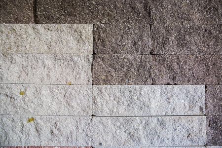 Part of the building wall faced with rectangular gray stone tiles different shades with rough front surface in a decorative pattern, texture, background,の写真素材