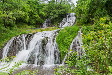 Upper and bottom cascades of the Dzhurynskyi, or Chervonohorodskyi waterfall on Dzhuryn river in spring overcast day, Ukraine, bottom view at long shooting exposureの写真素材