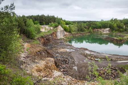 Fractionally operating basalt quarry, partially flooded by groundwater located among the forest, general view in spring overcast rainy dayの写真素材