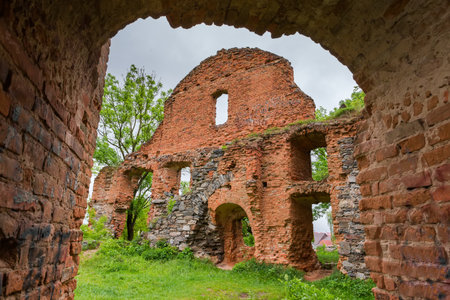 Ruins of brick and stone defense structures Korets Castle of 15th century, Ukraine. View from the courtyard side with arched wall on a foreground in spring rainy dayの写真素材
