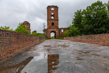 Brick gate tower of the ruined Korets Castle of 15th century, Ukraine. View from the main entrance side with castle bridge on a foreground in spring rainy dayの写真素材