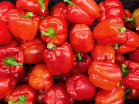 Freshly harvested raw red bell peppers in a container on a vegetable market, top view
