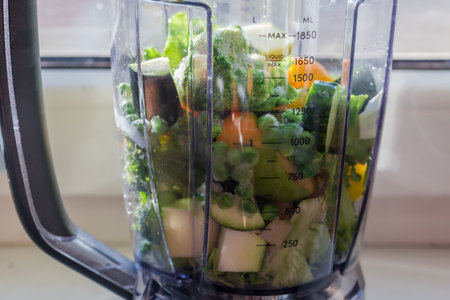 Various raw fresh and frozen vegetables and fruits for following making green smoothie in a...