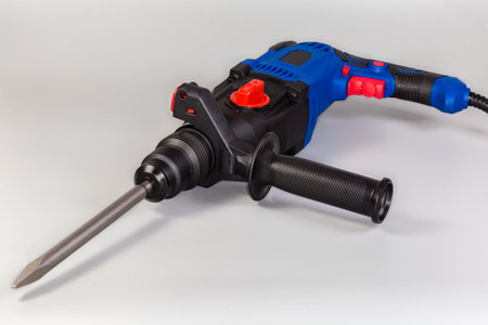 Electric rotary hammer drill in blue and black plastic housing with pointed chisel inserted in chuck...