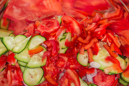 Different thinly sliced fresh vegetables in the large stainless steel kitchen bowl for subsequent preparing salad, or other dishes, fragment close-upの写真素材
