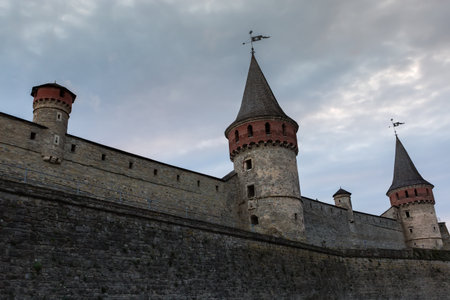Ancient fortress of the 14-18th centuries in Kamianets-Podilskyi, Ukraine. Northern defensive wall of the castle with bastion and two big and two small watchtowers against cloudy sky in eveningの写真素材