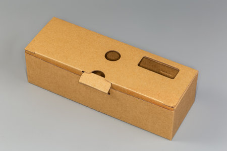 Closed empty rectangular long packing box made with light brown unbleached cardboard on a gray...